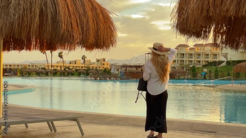 Relaxed Female Traveler Appreciating Peaceful Evening Ambiance Beside Pool And Palms
