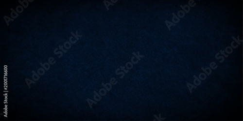 A dark blue grunge background features a rough textured denim fabric pattern with a weathered black canvas surface and old paper material design for a moody cloth wallpaper backdrop