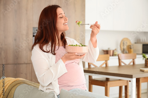 Young pregnant woman eating...