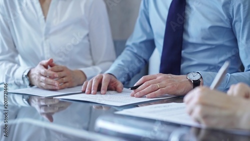 Business people are reviewing a contract papers and discussing the terms of the agreement. Lawyers at work
