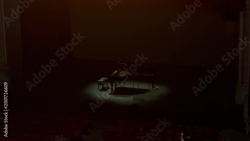 Grand piano and piano bench on empty wooden concert stage against plain wall. Studio stage setup. Classical music and live performance concept for poster and banner. 