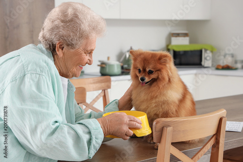Senior woman feeding Pomera...
