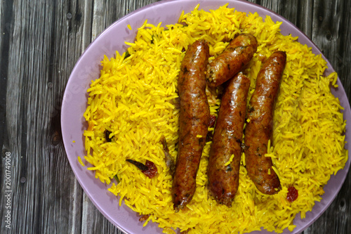 Egyptian classic sausage of deep fried stuffed mumbar which is basically intestines that are filled with spicy rice, herbs, onion, and tomato, on a bed of yellow Basmati long rice