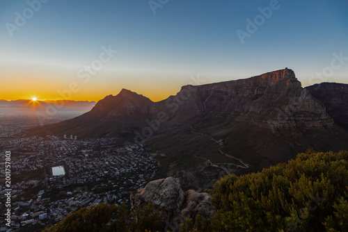An iconic sunrise seen from Lion's head over the skyline of Cape Town in South Africa with views on the spectacular and iconic Table mountain and Devil's head, while the sun peaks just over the hills 