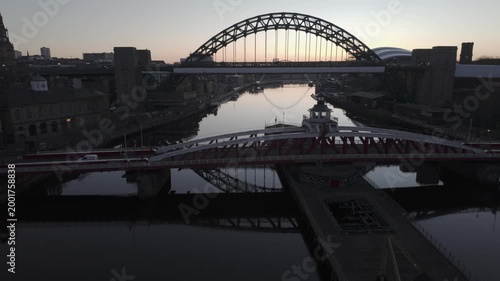 Swing Bridge and the high arch of the Tyne Bridge in Newcastle , with the Millennium Bridge and the modern silhouette of The Glasshouse (Sage) visible in the soft morning light.