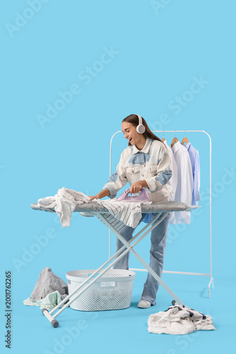 Pretty young woman ironing ...