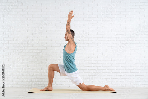 Young man doing yoga on mat...