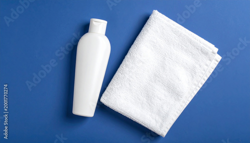 White Cosmetic Bottle and Cotton Towel on Blue Background