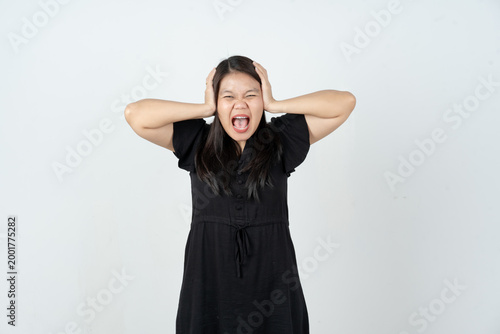 Stressed Asian woman screaming with hands on head against white studio background