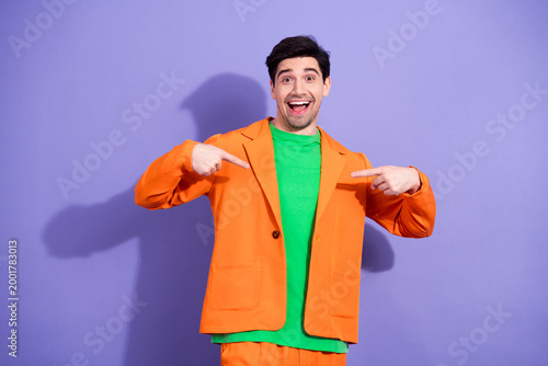 Foto Excited young man in bright orange suit and green shirt pointing at himself with