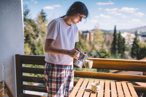 Woman pouring coffee on sunny terrace