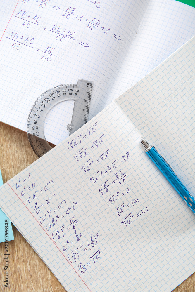 Fototapeta premium Open copybook with math formulas and pen on wooden table, closeup
