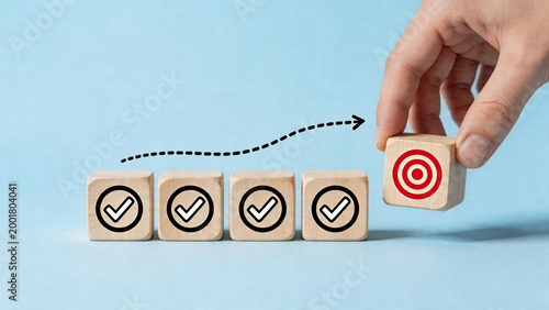 Business goal achievement success strategy concept with wooden blocks hand placing target block completion of tasks represented by checkmarks arrow indicating progress towards