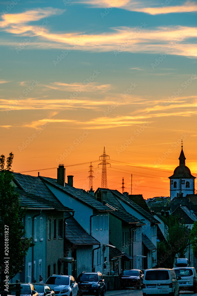 Naklejka premium Strommasten bei Sonnenuntergang über einer Stadt
