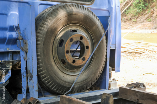 Photos Close up detail of old spare tire securely mounted on back of weathered blue tra
