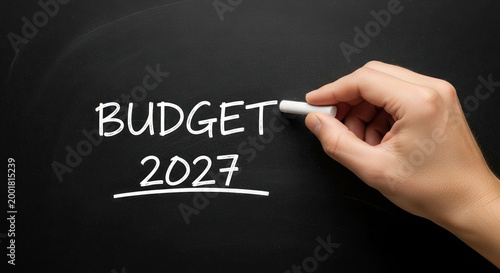 Hand writing budget plan for 2027 on black chalkboard with white chalk, clear focus on financial planning and organization