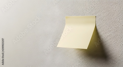 Yellow sticky note attached to textured wall background with copy space