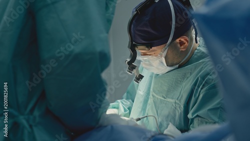 Photos Two medics in operation room working together skilled doctor man surgeon physici
