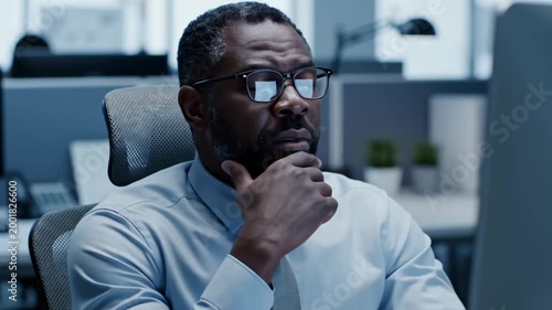 Serious Businessman Concentrated at Computer, Deep in Thought, at the Office Environment