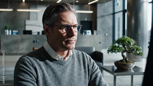 Serious Businessman With Glasses Concentrates While Working On A Computer in Modern Office