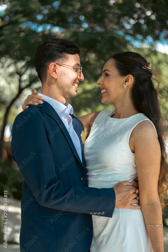 Naklejka premium Happy bride and groom walking and embracing outdoors in romantic wedding setting