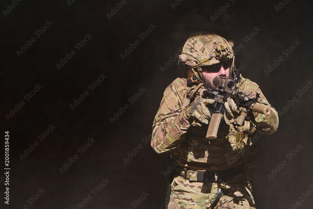 Fototapeta premium Camouflaged Soldier With Rifle in Tactical Gear Aiming During Military Training or Operation