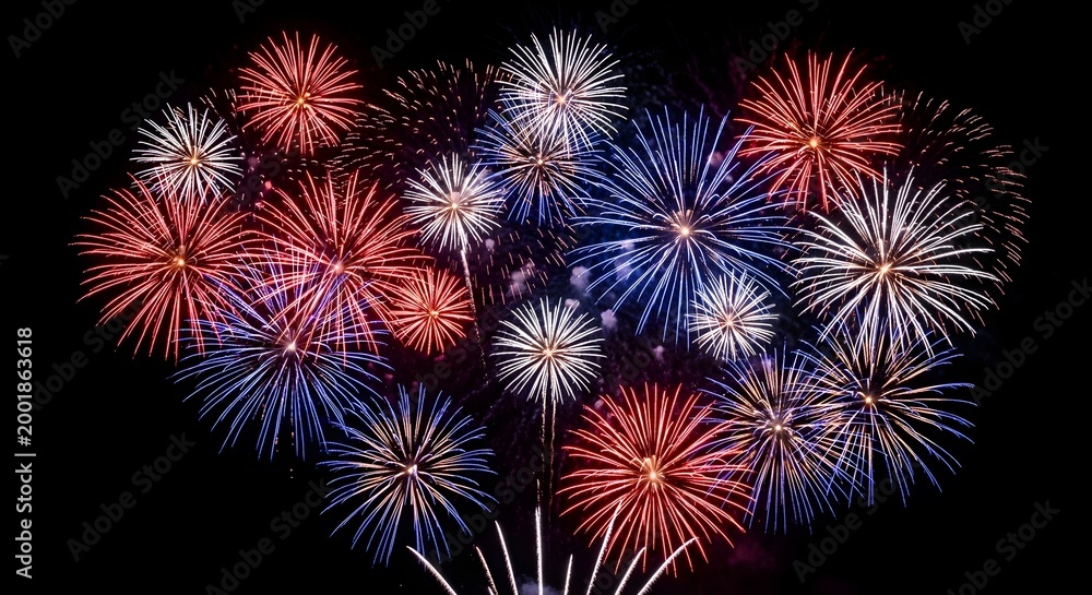 Fototapeta premium Vibrant red white and blue fireworks exploding in night sky on 4th of July American celebration