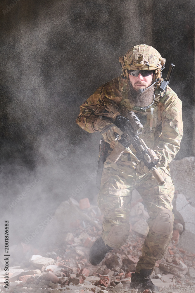 Fototapeta premium Armed Soldier in Tactical Gear Moving Through Dusty Urban Rubble With Rifle During Combat Operation