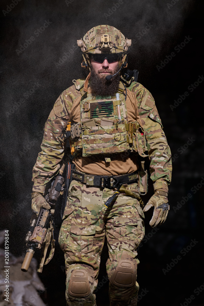 Fototapeta premium Armed Soldier in Tactical Gear Walking Through Dust With Rifle and Ballistic Helmet