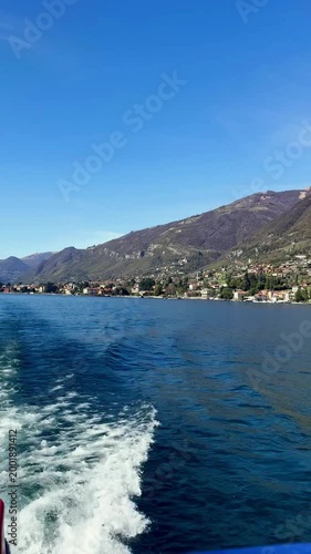 Lake como view from boat with blue water mountain landscape coastal village and wake trail under clear sky scenic travel destination in italy