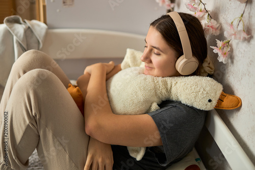 Teen girl listening to music hugging plush toy