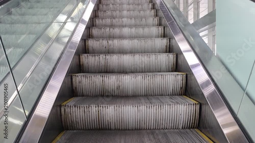 Escalator moving featuring textured metal steps and yellow warning lines, highlighting elements of urban travel, modern architecture, and public transportation infrastructure