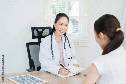  A female doctor is talking to a smiling female patient in a hospital using a tablet PC. Concepts related to medicine and healthcare.