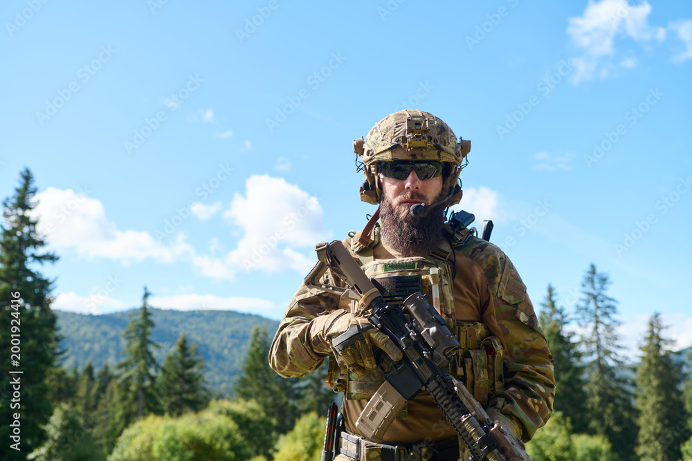 Fototapeta premium Bearded Soldier in Tactical Gear Holding Rifle in Forest During Military Training Exercise