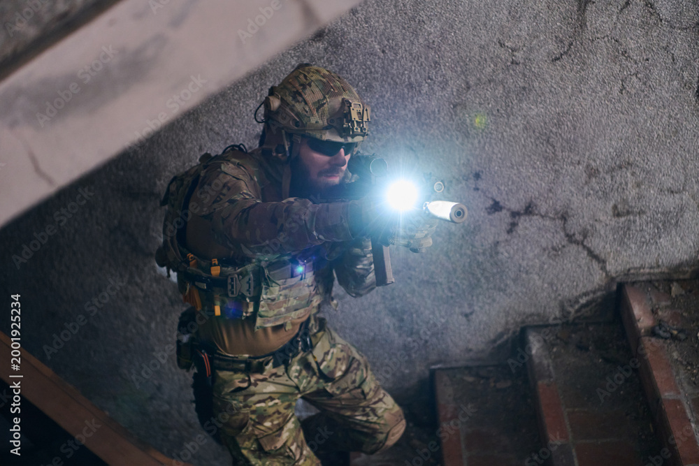 Fototapeta premium Tactical Soldier In Full Military Gear Aiming Rifle With Flashlight During Urban Close Quarters Operation
