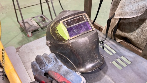 Photos helmet and gloves, Close up of old welding helmet with scratched lens and tape p