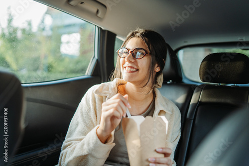 Woman eating takeout food in car back seat
