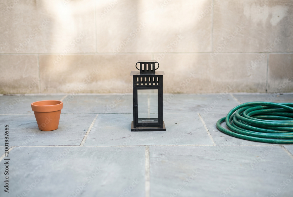 Naklejka premium Top View of Grey Stone Patio Featuring Terracotta Plant Pot and Coiled Green Garden Hose Representing Home Gardening Maintenance Outdoor Living and Backyard Chores Isolated