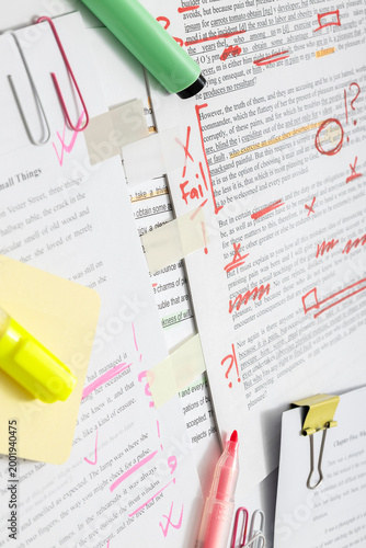 Copyediting process, reviewing manuscript with annotations, corrections and feedback on printed document in office setting. Vertical image