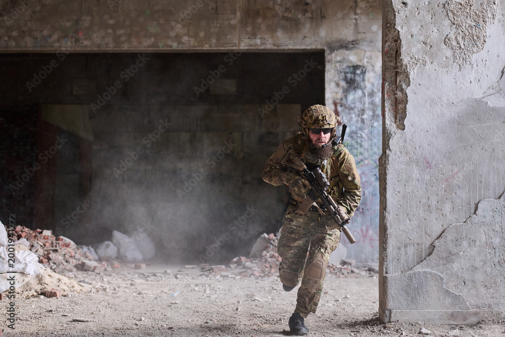 Fototapeta premium Soldier In Tactical Gear Running Through Abandoned Urban Building During Urban Combat Training Exercise