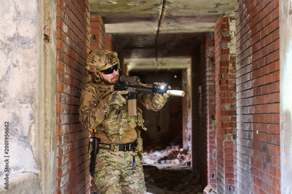 Fototapeta premium Tactical Soldier In Urban Combat Gear Clearing Abandoned Building With Rifle And Flashlight