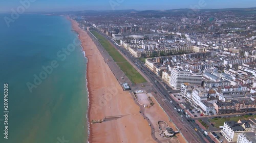 Wide aerial sweep of Brighton coastline featuring sandy beach and city traffic