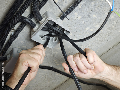 Fotografi Man connects electrical cables in junction box for home installation and power m