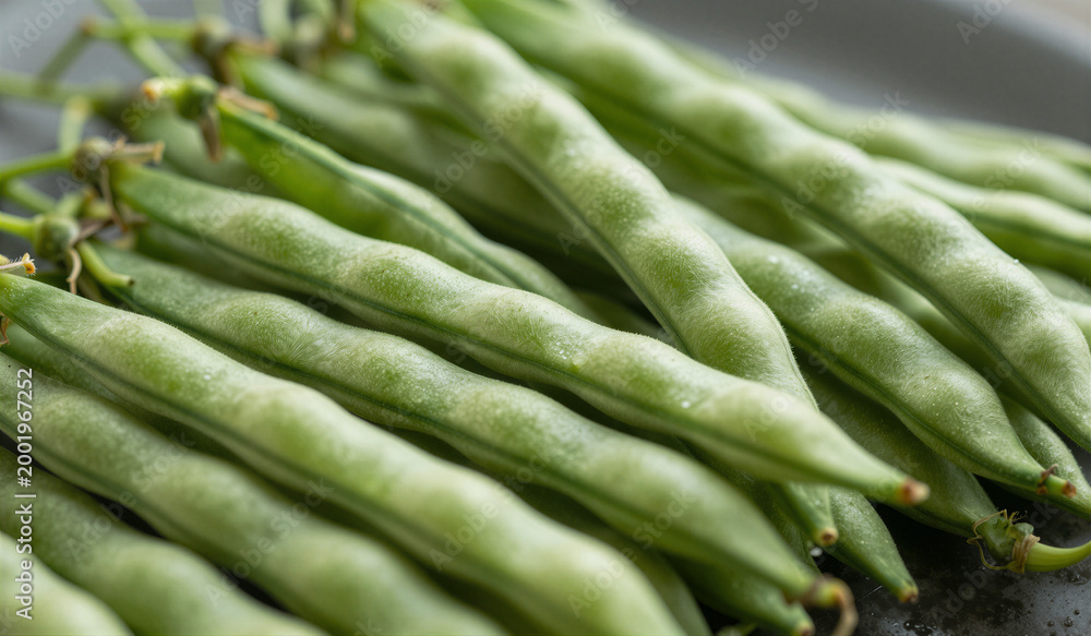 Fototapeta premium Fresh green beans piled on dark plate with blurred background