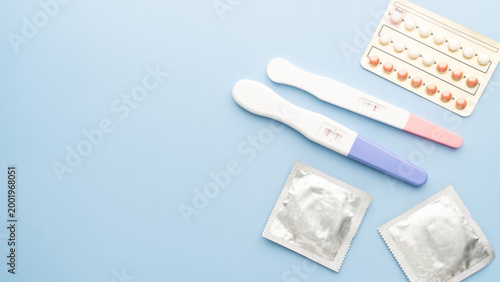 Quadro su tela Pregnancy test with birth control pills and condoms on blue background