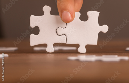 Hand fitting two puzzle pieces together. Teamwork, cooperation, solution, ideas and connection conce