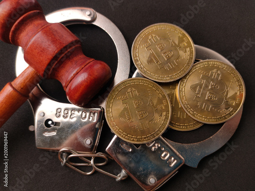 Foto Physical gold Bitcoin BTC coins resting a top a pair of silver metal handcuffs a