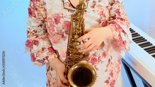 キーボードの前でアルトサックスを演奏している女性