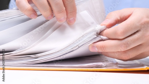Konstfotografi Hands flipping through clear plastic file sleeves in a binder, organizing and se