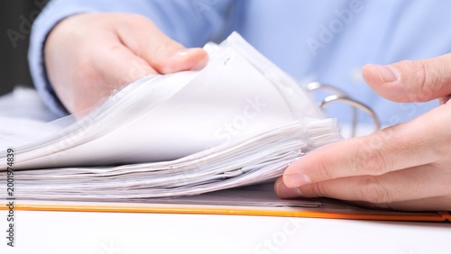Schilderij op canvas Person's hands organizing and reviewing paperwork in a binder, browsing through